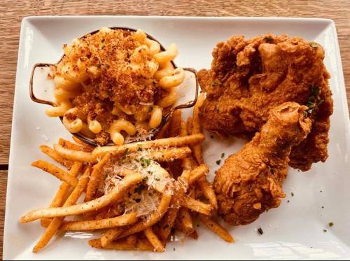 A plate featuring crispy fried chicken, macaroni and cheese, and seasoned French fries.
