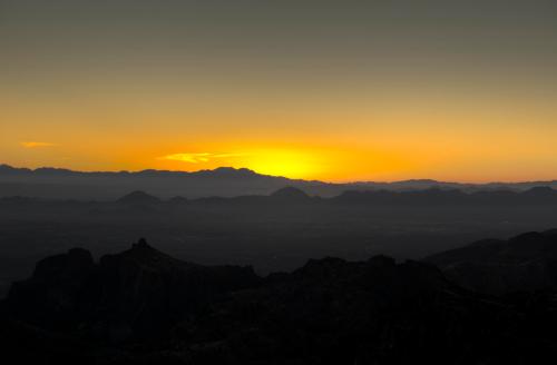 A serene sunset over mountain silhouettes, casting warm hues across the horizon.