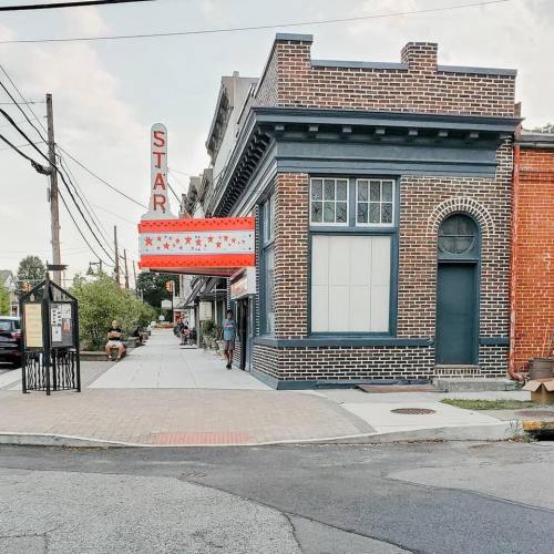 Historic brick building with a marquee sign reading "STAR," located at a street corner with pedestrians nearby.