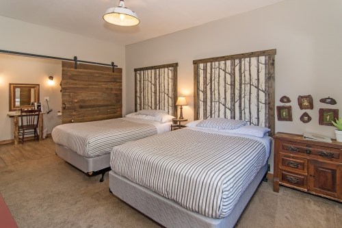 Cozy bedroom with two beds, rustic decor, wooden accents, and a warm atmosphere.