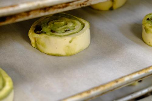 Close-up of unbaked green tea rolls on a baking tray lined with parchment paper.