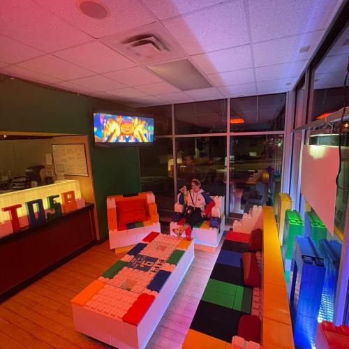 A colorful lounge area with LEGO furniture, a TV displaying animated content, and vibrant lighting.