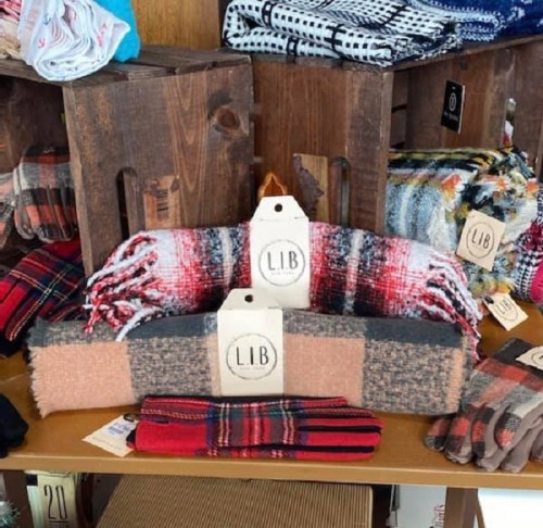 A display of cozy scarves and gloves in various patterns and colors, arranged on wooden crates.