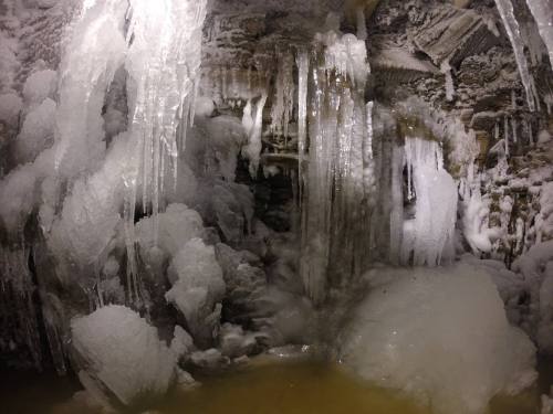 A frozen cave with large icicles and ice formations, reflecting a cold, wintry atmosphere.