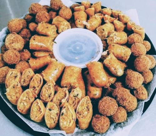 A platter of assorted fried snacks, including spring rolls and croquettes, arranged in a circular pattern.