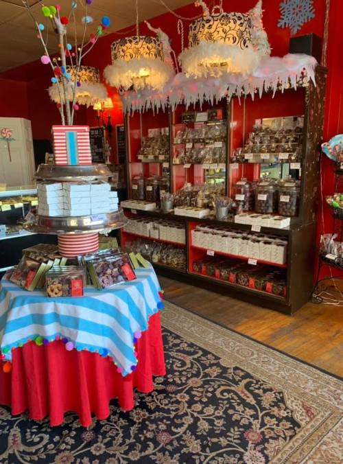 A colorful candy shop interior with a decorated display table and shelves filled with various sweets and treats.