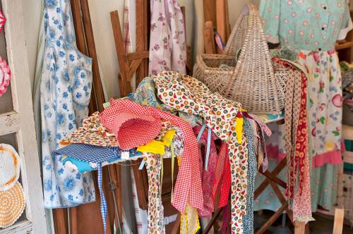 A colorful assortment of fabric scraps and aprons displayed on a table in a cozy craft space.