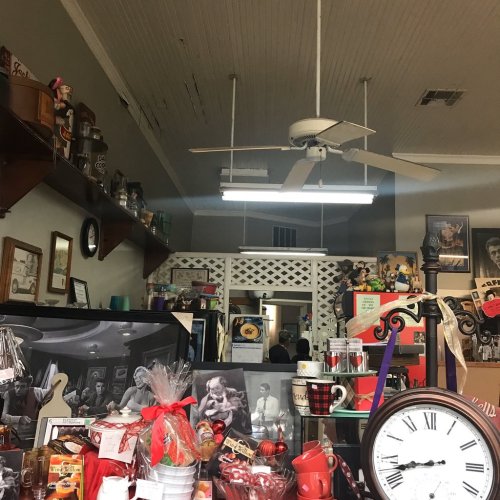 A cozy shop interior with shelves of items, a ceiling fan, and various decorations, creating a nostalgic atmosphere.