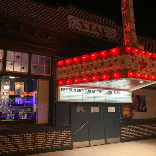 A vintage theater marquee lit up at night, displaying "FRI SUN AND SUN AT TWO LION XING."