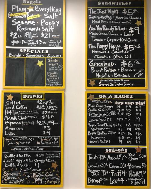 Menu board featuring bagels, sandwiches, drinks, and toppings with prices listed for each item.