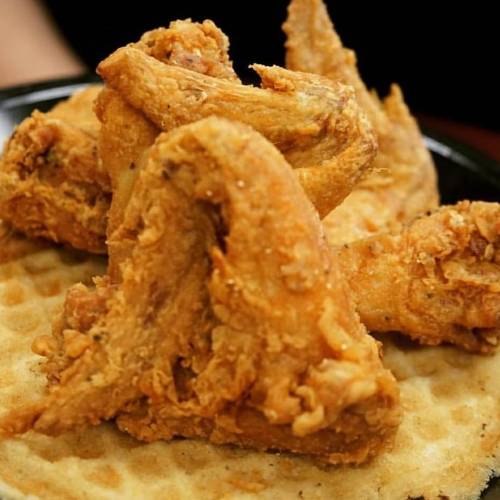 Crispy fried chicken wings served on a golden waffle, creating a delicious comfort food dish.