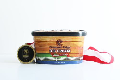 A tub of Crescent Ridge ice cream next to a gold medal with a red and white ribbon, labeled "2nd Place."