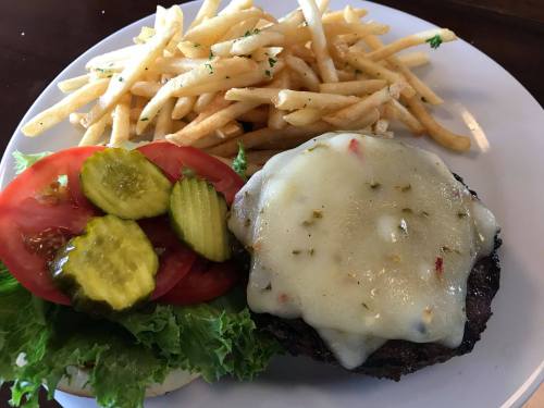 A juicy burger with melted cheese, lettuce, tomato, and pickles, served with a side of crispy French fries.