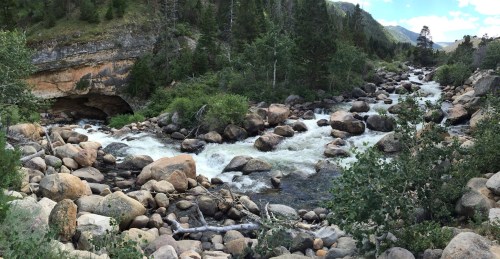 A scenic river flows through a rocky landscape, surrounded by lush greenery and steep hills.