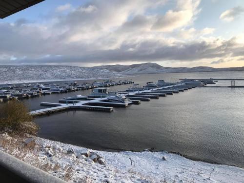A snowy marina with boats docked, surrounded by hills and a cloudy sky.