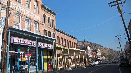 Historic street view featuring brick buildings, shops like "Silver Queen," and a clear blue sky.