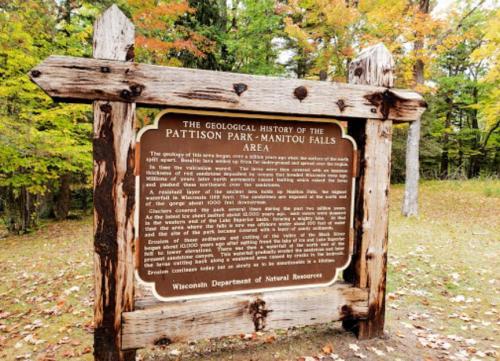 Sign detailing the geological history of Pattison Park, surrounded by colorful autumn foliage.