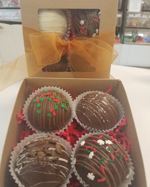 A gift box of assorted chocolate truffles, decorated with festive sprinkles and a gold ribbon.