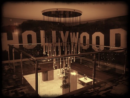 A modern interior with a glass chandelier and a large "HOLLYWOOD" mural on the wall.