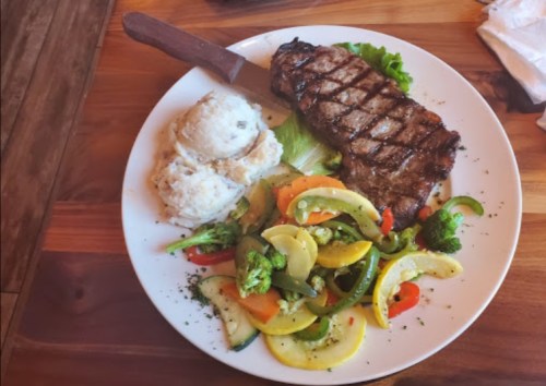 A plate featuring grilled steak, mashed potatoes, and a colorful medley of sautéed vegetables.