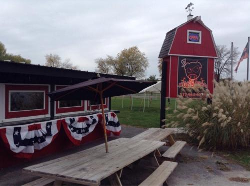 A red building with a sign for a BBQ restaurant, featuring picnic tables and decorative bunting.