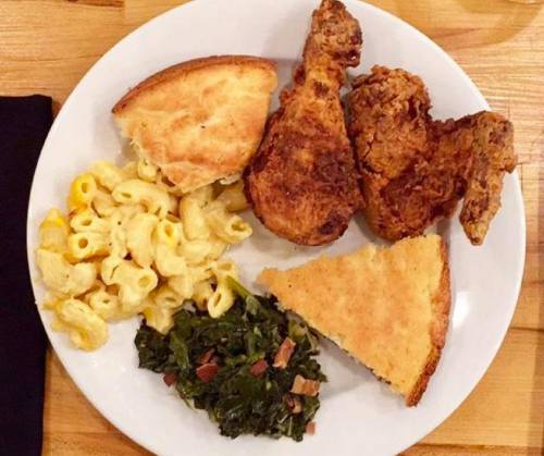 A plate of fried chicken, cornbread, macaroni and cheese, and collard greens.