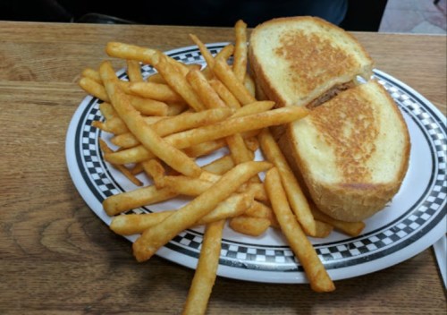 A plate with golden French fries and a grilled cheese sandwich cut in half.