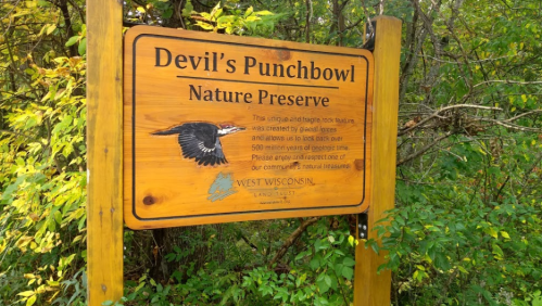 Sign for Devil's Punchbowl Nature Preserve, featuring a bird illustration and information about the area's geological history.