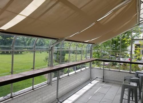 A sunlit indoor space with large windows, a wooden bar, and a view of a green lawn outside.