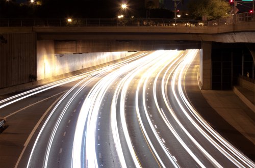 Long exposure shot of a highway underpass at night, with streaks of light from moving vehicles.