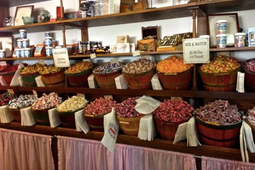 A colorful display of assorted candies in baskets on shelves, with signs for pricing and mix-and-match options.
