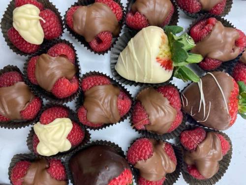 A variety of chocolate-covered strawberries and raspberries arranged in a decorative display.