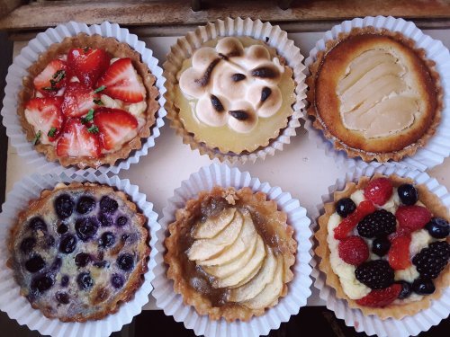 A variety of six mini tarts, featuring fruits like strawberries, blueberries, and blackberries, with different toppings.
