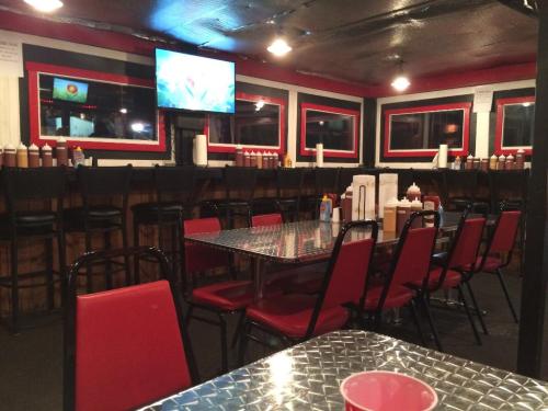 A casual dining area with red chairs, a metal table, and a TV, featuring condiment bottles along the walls.