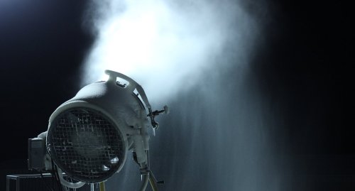 A large machine emits a cloud of mist or vapor against a dark background.