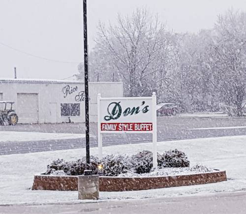 Sign for Don's Family Style Buffet in a snowy landscape, with buildings and a tractor in the background.