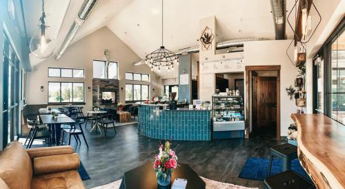Bright, modern café interior with a cozy seating area, a counter displaying pastries, and large windows for natural light.