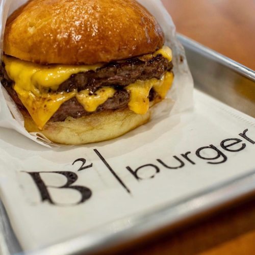 A delicious cheeseburger with two beef patties and melted cheese, served on a toasted bun with a branded wrapper.
