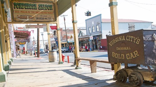 A historic street scene in Virginia City, featuring the Ponderosa Saloon and a gold car display.
