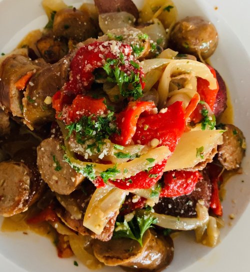 A colorful dish featuring sausage, roasted red peppers, onions, and herbs, garnished with grated cheese.