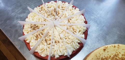 A red velvet cake topped with cream cheese frosting, decorated with crumbs and sliced into triangular pieces.