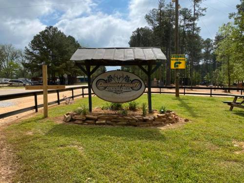 Sign for Ditchtown Plantation surrounded by greenery, with a gravel path and trees in the background.