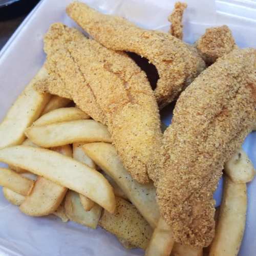 Fried fish fillets served with golden French fries in a takeout container.