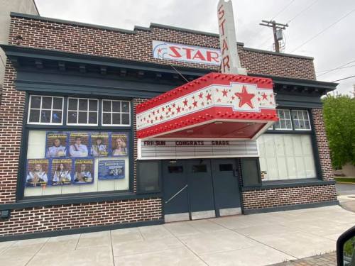 Exterior of the Star Theater featuring a marquee celebrating graduates, with posters and a brick facade.