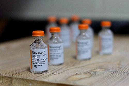 Vials of NovoLog insulin on a wooden surface, labeled for diabetes management.