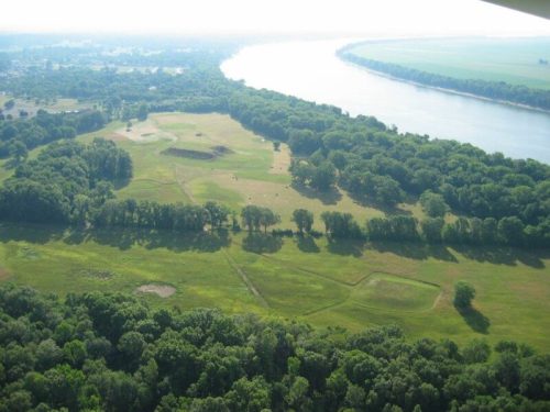 Aerial view of a lush green landscape with a river winding through trees and open fields.