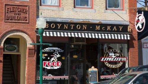 A storefront featuring "Boynton McKay" with a coffee bar sign and vintage architecture in a quaint town.