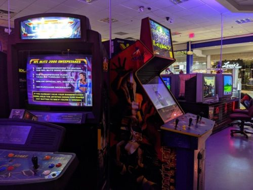 A retro arcade with various game machines, including a large screen displaying a sweepstakes announcement.