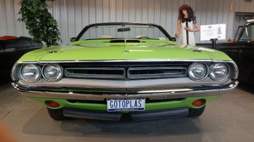 A bright green classic convertible car with a mannequin in a retro outfit in the background.