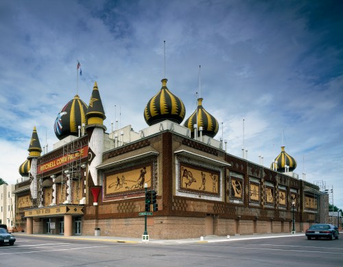 A large building with distinctive golden domes and colorful murals, set against a cloudy sky.